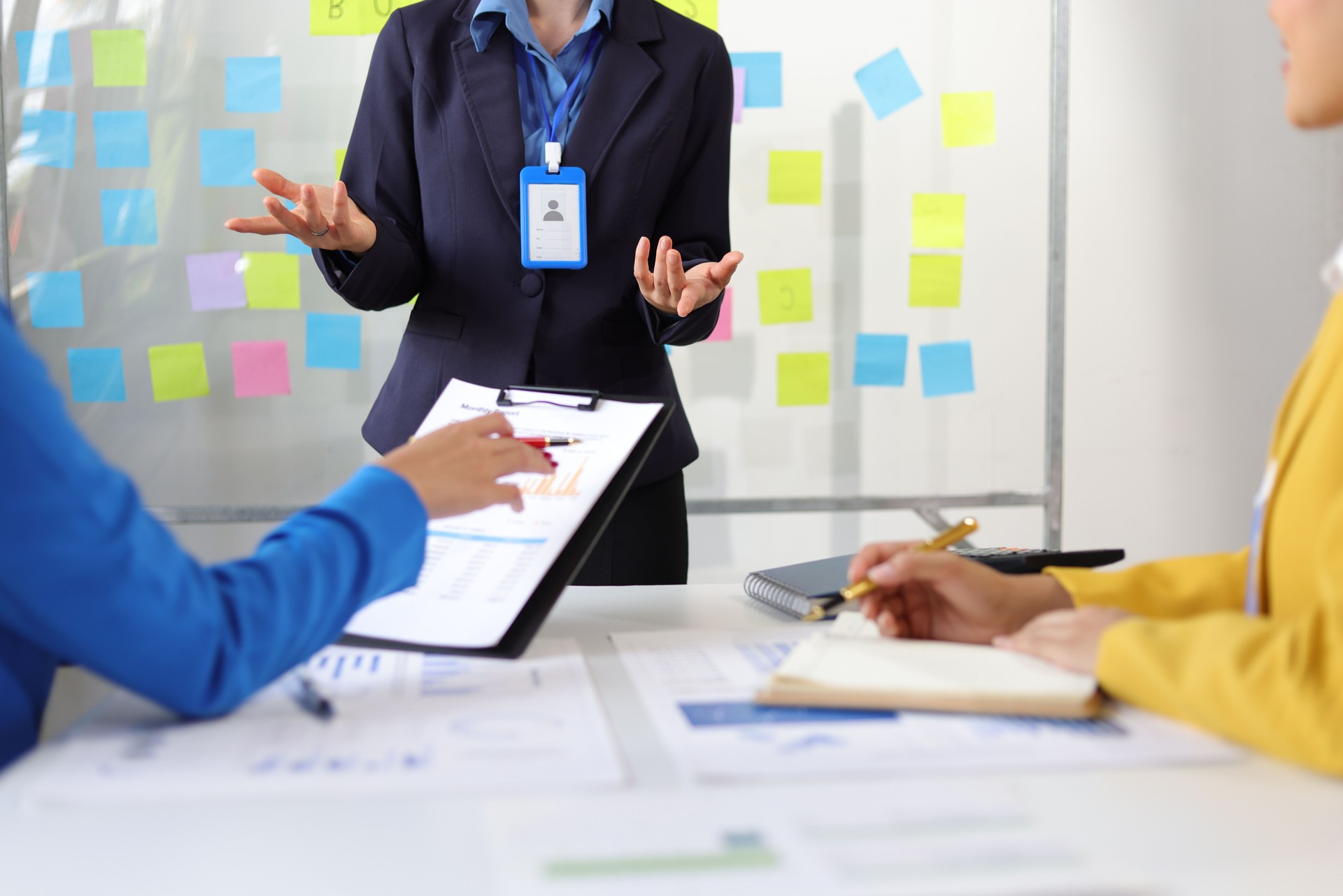 Businesswoman presenting to colleagues in conference room with charts and data