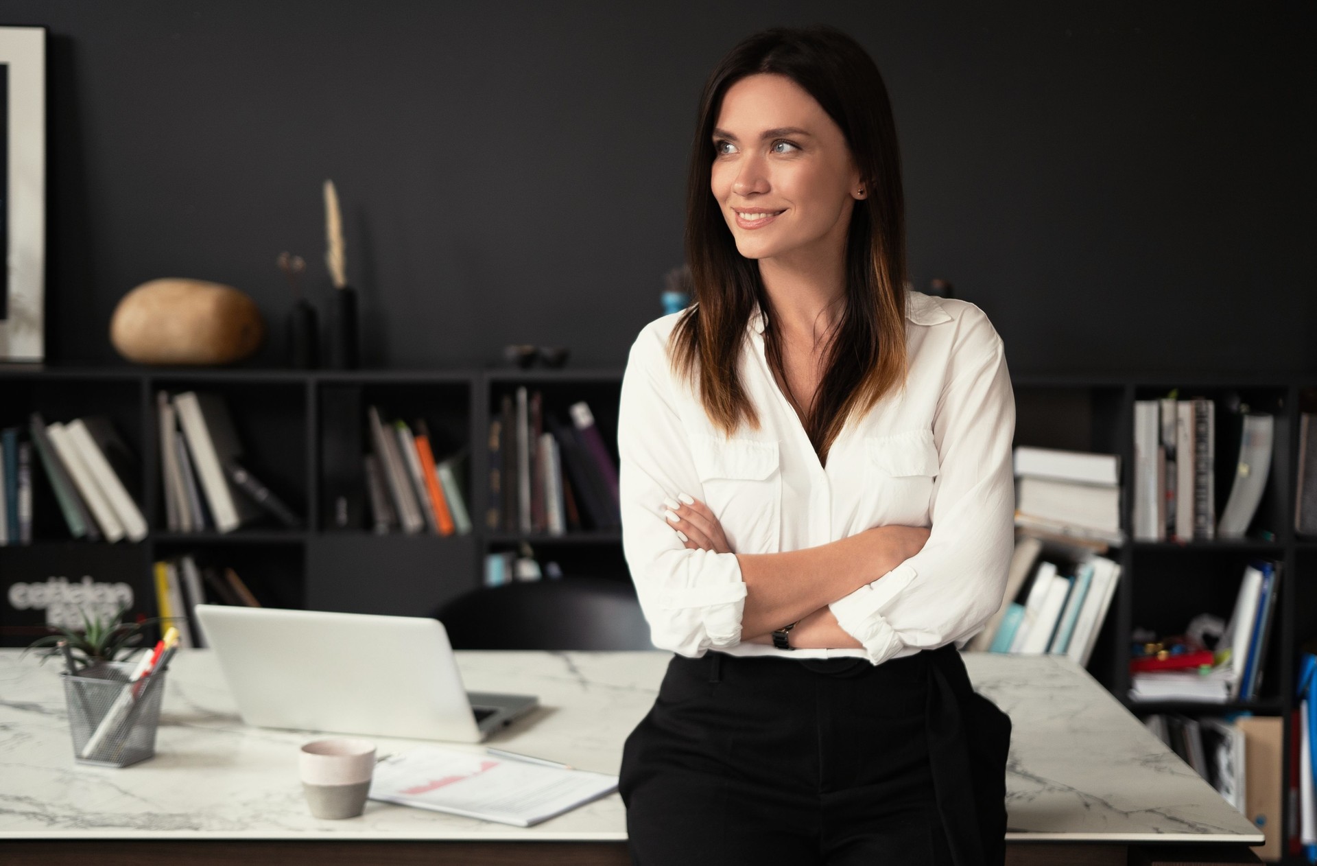 Confident stylish european middle aged woman standing at workplace, 30s lady executive leader manager looking at camera