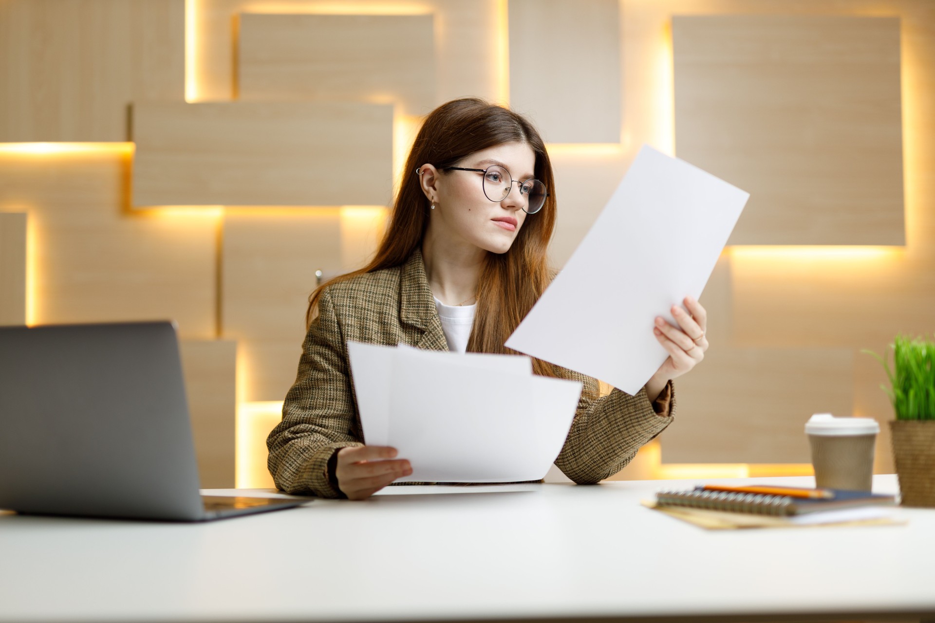 Rapports bureaucratiques, une jeune femme en veste comprend les comptes sur le lieu de travail, la paperasse.